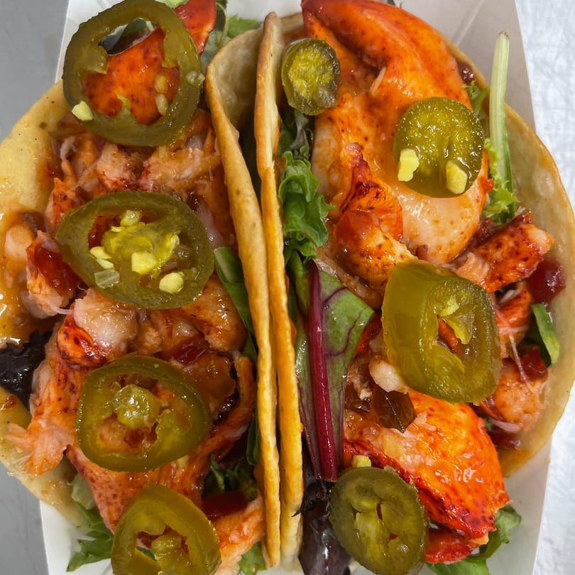 Two Mystic Lobster Roll Co. tacos filled with lobster, greens, and jalapeños.